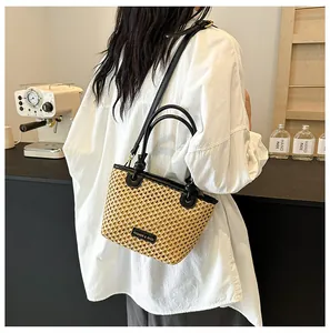 Close-up of woven bucket bag featuring black leather handles and fashion logo patch detail