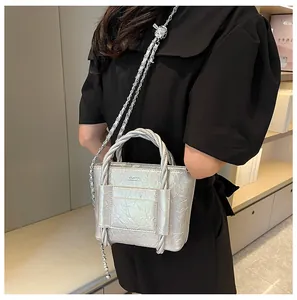 Detail of silver pleated tote bag featuring woven handle and metallic chain strap