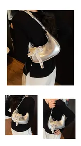 Detail of silver metallic dumpling bag with lace bow and pearl pendant accessory