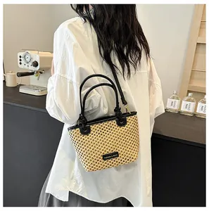 Close-up of hand-woven straw bucket bag featuring black PU leather straps and fashion label