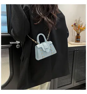 Detail der hellblauen Mini-Quadrat Tasche mit goldener Kette an einem stylischen Model