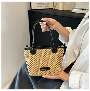 Close-up of woven straw bucket bag with black leather trim and top handles
