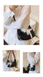 Detail of black patent leather crescent bag with white bow and pearl heart charm