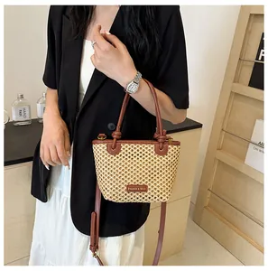 Close-up of woven bucket bag with brown leather trim and adjustable crossbody shoulder strap