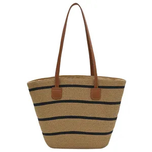 Woven straw tote bag with black stripes and brown leather straps for summer beach vacations