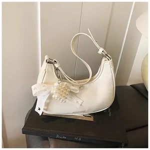 Detail of cream pleated hobo bag with lace bow and pearl pendant accessories