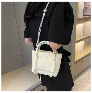 Detailed side view of off-white pleated bucket bag with silver chain strap on model