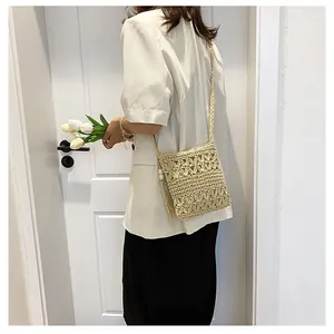 Detail of handmade hollow floral crochet patterns and tassel on a beige straw crossbody bag