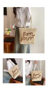 Detail of hollow woven tote bag featuring brown Bon jour embroidery and dual straps