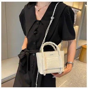 Detail of white textured leather bucket bag with CLASSIC lettering and chain strap