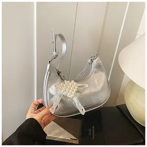 Detail of silver metallic crescent bag featuring lace bow and pearl heart charm decor