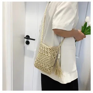 Detail view of woven straw crossbody bag with side tassels and wooden bead accents