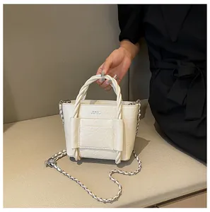 Close-up of creamy white bucket bag with pleated leather texture and braided handle