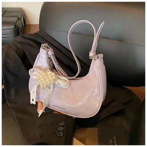 Detail of lilac crescent bag featuring pearl heart charm and lace bow decoration
