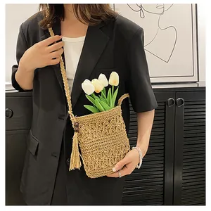 Detailed macro of hollow straw woven crossbody bag with stylish fringe and natural texture