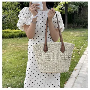 Detail of hand-woven straw bag featuring hollow floral pattern and brown leather straps