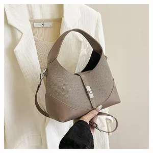 Close-up of textured fabric and leather trim with metal twist lock on top-handle bag