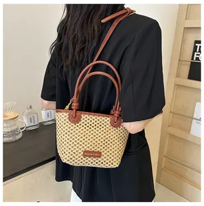 Detail of hand-woven straw bucket bag with dark brown leather trim and fashion logo