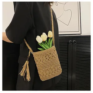 Detail of woven straw shoulder bag featuring hollow out pattern and tassel ornament