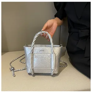 Detail of silver metallic textured bucket bag with woven handle and classic text