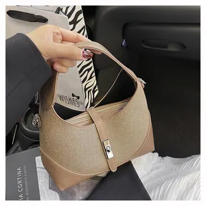 Detail of khaki woven texture handbag with silver metal lock and leather handles