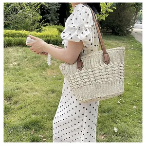 Detail of hand-woven hollow straw tote bag featuring leather shoulder strap for casual use
