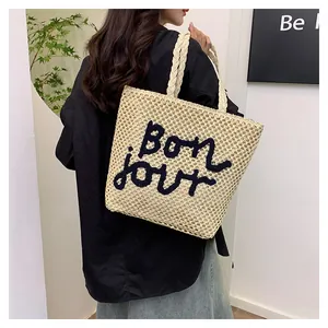 Detail of hollow woven tote bag featuring Bonjour embroidery and thick rope handles