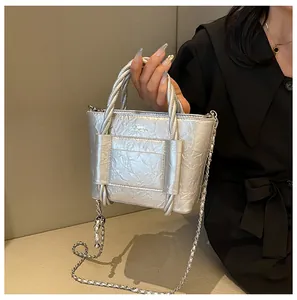 Silver metallic pleated bucket bag featuring woven handle and chain shoulder strap
