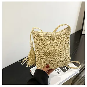 Detail of hand-woven straw bag featuring hollow flower patterns and large wood bead tassel