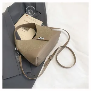 Detail of khaki leather bag with metal buckle fastener on grey suit background
