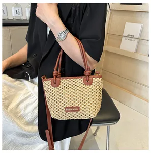 Detail of woven bucket bag with brown leather handles and adjustable shoulder strap