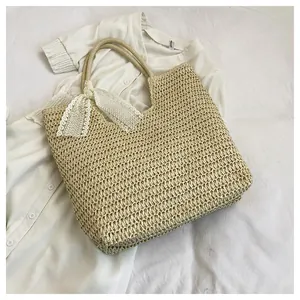 Detail of natural woven straw tote bag featuring a white lace ribbon and textured finish