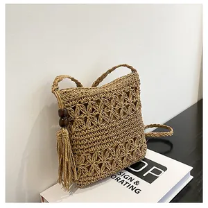 Detail of hollow star pattern straw woven bag with fringe tassels and wooden beads