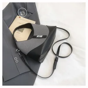 Detail of the chic geometric handbag with silver twist lock on a textured grey fabric