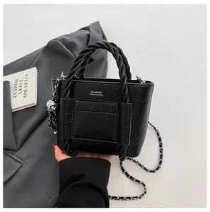 Detail of black wrinkled patent leather bucket bag with braided handle and chain strap