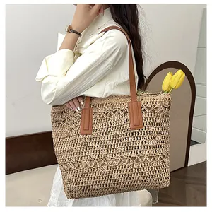 Close-up of woven straw tote bag featuring intricate cut-out patterns and leather straps