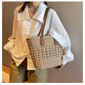 Detail of hand-woven straw tote bag with hollow knit patterns and leather shoulder straps