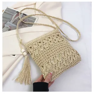 Detailed view of handmade straw crossbody bag with hollow flower patterns and long tassels