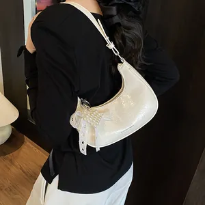 White crescent shoulder bag with pearl bow charm and chic patent leather texture