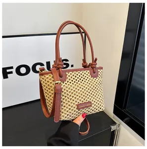 Detail of woven straw bucket bag with red-brown leather trim and golden metal buckles