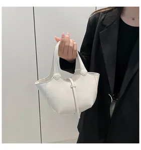 Detailansicht der weißen PU-Leder-Eimertasche mit dekorativen langen Riemen im Fokus