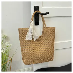 Close-up of handwoven straw tote bag with white lace ribbon detail and twin handles