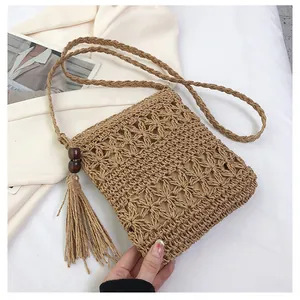 Detail view of woven straw bag featuring hollow floral pattern and side tassel with beads