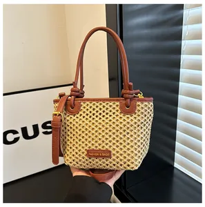 Close-up of woven bucket bag with brown leather handles and a fashion label detail