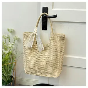 Detail of hand-woven straw tote bag with elegant lace bow on a white door handle