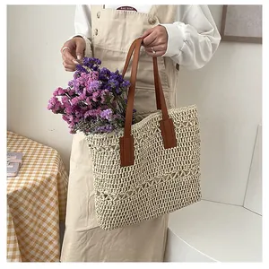 Detail of hand-woven straw tote bag showing large capacity and brown leather handles