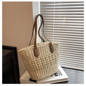 Detailed close-up of woven straw texture and premium brown leather handle stitching