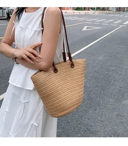 Détail du sac cabas en paille tressée avec ses bandoulières en cuir marron foncé