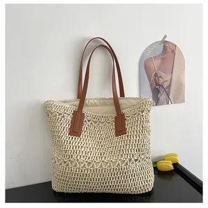 Detail of hollow woven straw tote bag featuring brown leather straps and inner lining