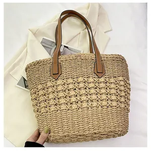 Detailed view of hollow hand-woven straw tote with premium brown leather handles
